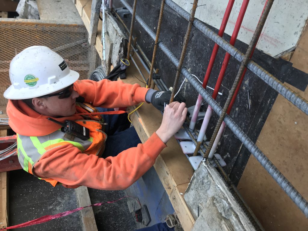Construction worker installs concrete sensor on rebar