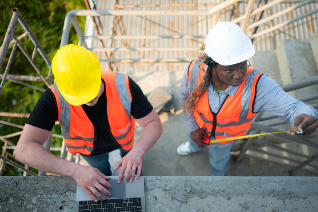 Male and female engineers working on construction site, They are inspecting the cement plaster work on the walls and balconies of the building.
