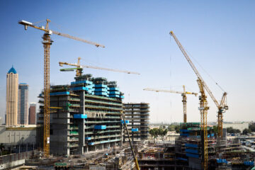 Construction site with cranes and people working. Dubai, United Arab Emirates