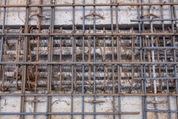 Detailed view of reinforced steel rebar embedded in concrete, forming a grid structure for strength in construction foundations.