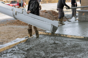 Pavement is being laid around new house with help of concrete mixing truck